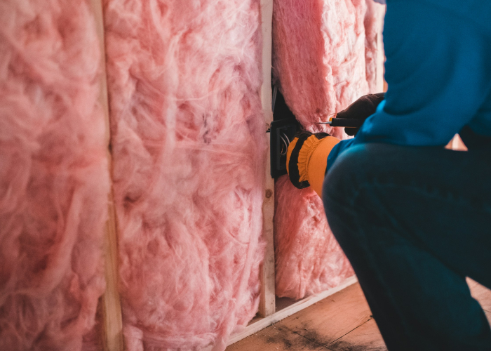 Insulation-Services, Batt Insulation inside wall cavity being installed (person with gloves on)